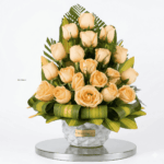 Elegant peach rose arrangement in a clear glass cylinder vase with fresh greenery