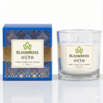 A lit oudh scented candle in an amber glass jar, casting a warm glow.